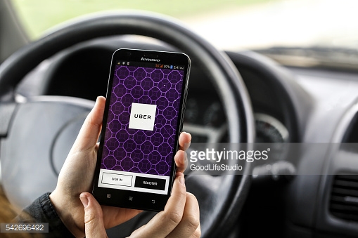 Close-up of an unrecognizable woman using the Uber App on her Lenovo A916 smartphone in a car. Uber mobile app allows consumers with smartphones to submit a trip request which is then routed to Uber drivers who use their own cars.